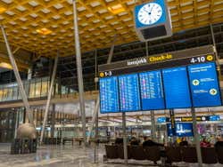 A blue information board under a clock inside the airport terminal