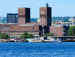 A large brown brick buidling with two rectangular towers behind a large harbour area