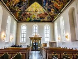 A painted roof over pews in a small church