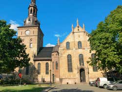 A yellow-stone church with a tower on the left under a blue sky
