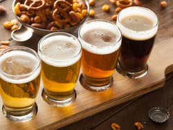 A wooden board with four glasses of different coloured beer