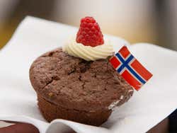 A small cake with a Norwegian flag, a blob of cream and a raspberry