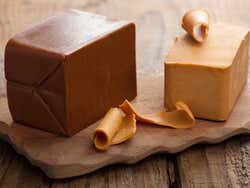 Two rectangular blocks of light brown cheese on a wooden board